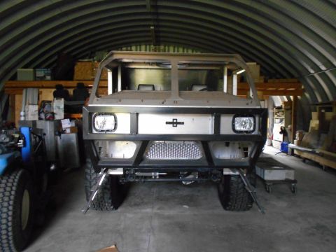 1992 Ford Bronco - Front view of a custom-built vehicle, possibly a truck or SUV, in a workshop setting. The vehicle features a prominent black metal bumper,…
