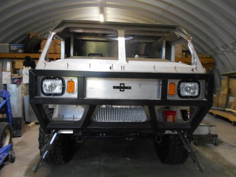 1992 Ford Bronco - Front view of a custom-built vehicle resembling a Humvee, with a large black metal bumper and square headlights. The vehicle appears to be…