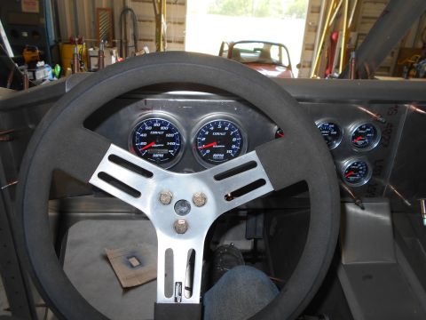 1992 Ford Bronco - The interior of a custom vehicle shows a large steering wheel in the foreground, with a dashboard featuring multiple gauges including a spe…