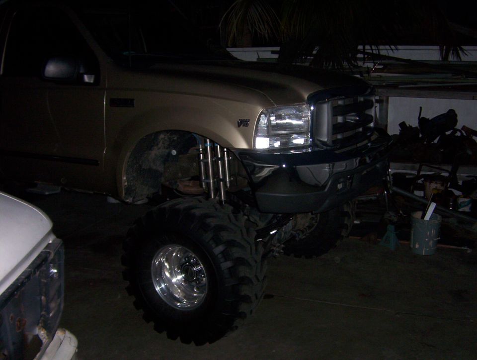 Lifted gold Ford Super Duty on huge bar-tread tires, fender removed
