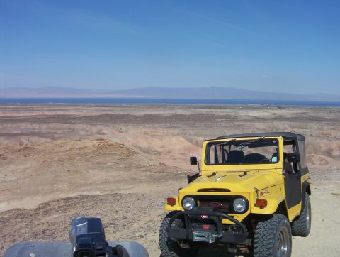 2000 Ford F-450 - This yellow Toyota Land Cruiser FJ40 is parked in a desert landscape overlooking a body of water and distant mountains.
