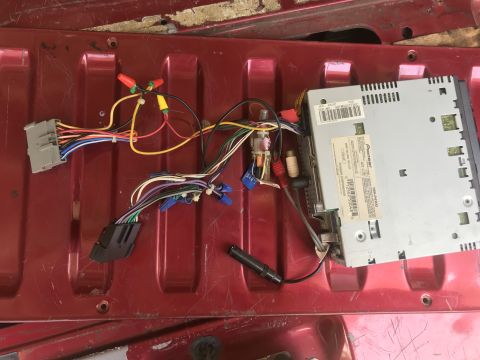 1994 Ford Bronco - A disassembled Pioneer car stereo with its wiring harness is laid out on a red, textured surface, likely the bed of a truck.