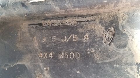 1985 Ford Bronco - Close-up of a vehicle part showing embossed text including 'F41A-CA', '4 9 5 0/5 8', and '4X4 M50D'. There is also a circular emblem visibl…