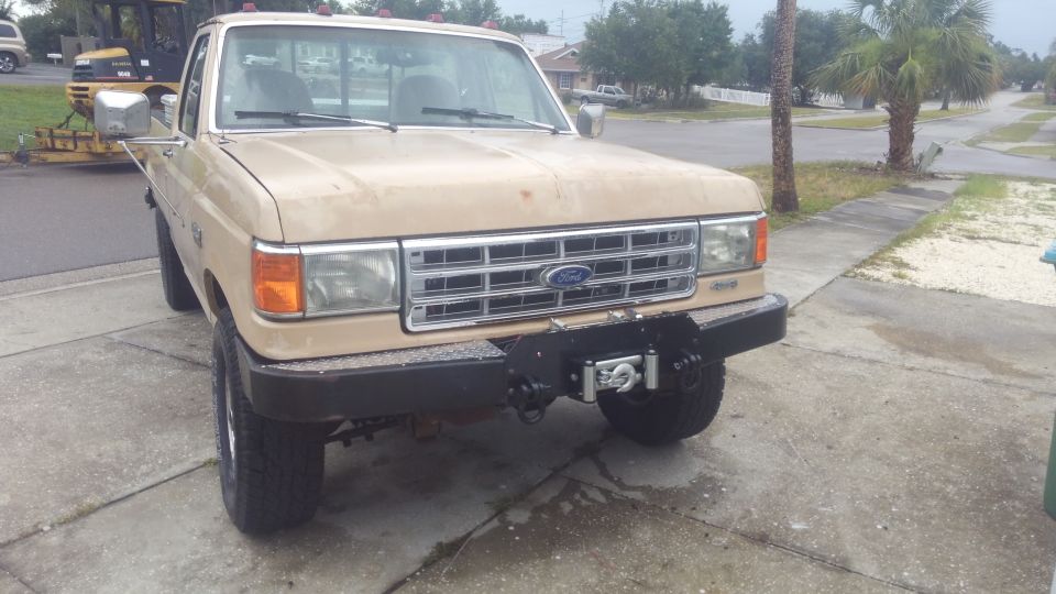 Tan 1990 Ford F-250 pickup truck with aftermarket bumper and winch parked on driveway.