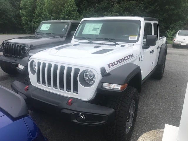 White Jeep Wrangler Rubicon parked next to a dark gray Jeep Wrangler.