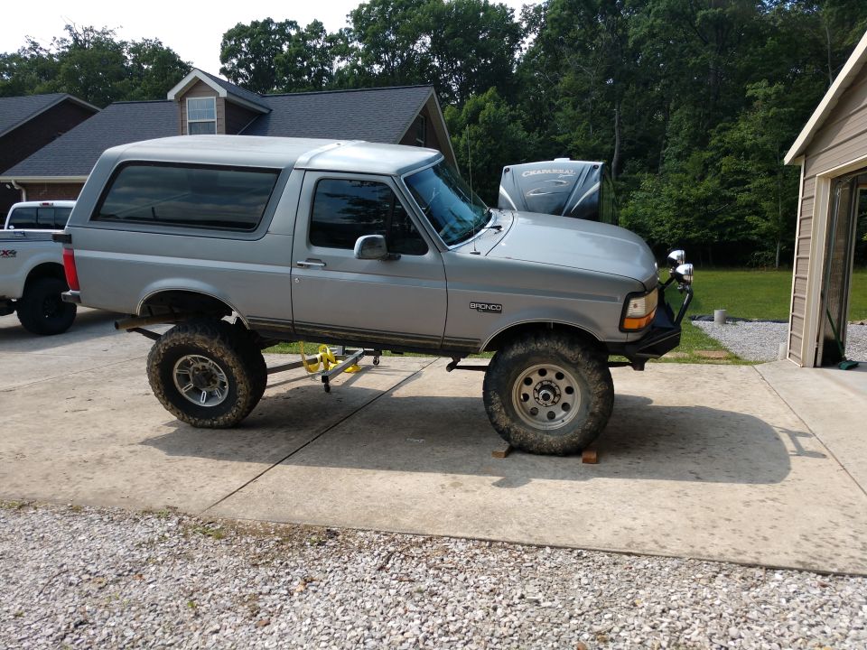 Silver 1995 Ford Bronco with lift kit and custom bumper parked on driveway.