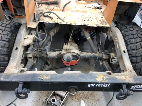 1992 Jeep Wrangler - The rear axle and suspension components of an orange Jeep Wrangler are visible from a high-angle shot. The frame has a black bumper with th…