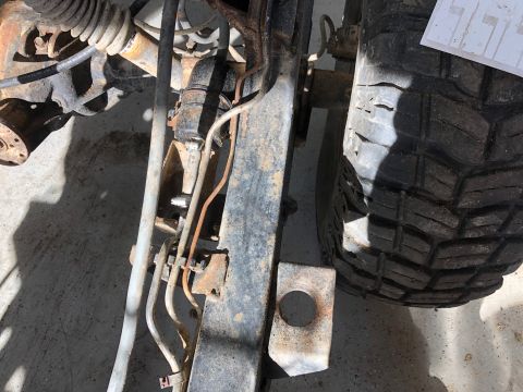 1992 Jeep Wrangler - This is a close-up, low-angle shot of the undercarriage of a Jeep Wrangler, focusing on the suspension and frame components. The vehicle ap…