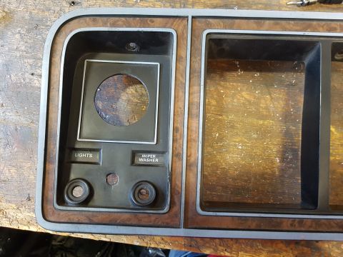 1978 Ford Bronco - A close-up view of a vintage automotive dashboard panel with wood grain trim. The panel has cutouts for gauges and buttons labeled "LIGHTS"…