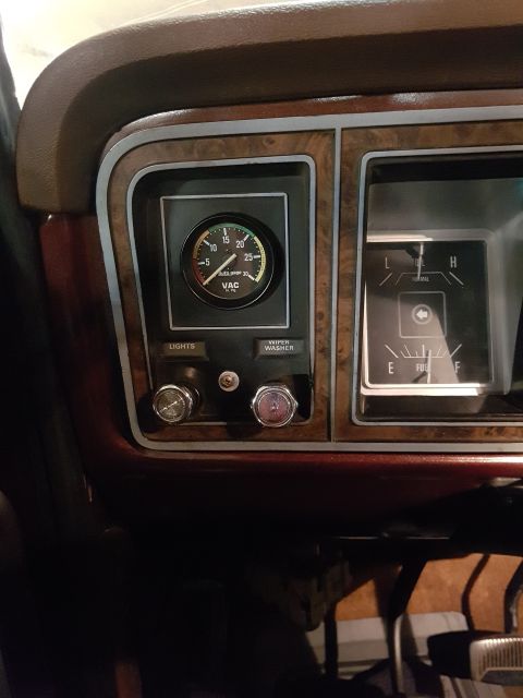 1978 Ford Bronco - The interior of a classic Ford Bronco shows a dashboard with a vacuum gauge, fuel gauge, and control knobs for lights and windshield wipers.