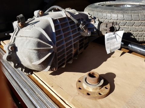 1978 Ford Bronco - A used transfer case, likely for a 1978 Ford Bronco, sits on a wooden surface next to a spare tire. A tag is attached to the transfer case…