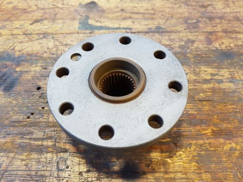 1978 Ford Bronco - A metal flange with a splined center bore and eight bolt holes is shown on a wooden surface.