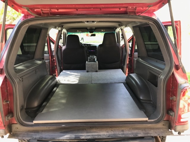 Rear cargo area of red Ford Explorer with folded seats and flat load floor