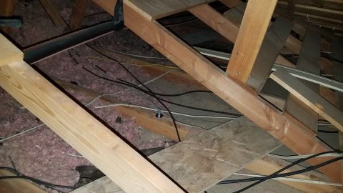 1985 Ford Bronco - This image shows the interior of an attic with wooden beams, insulation, and electrical wiring. There are no vehicles or vehicle parts visi…