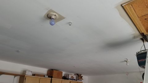 1985 Ford Bronco - The image shows a white ceiling with exposed light fixtures and some storage boxes on shelves below. A garage door opener mechanism is visi…