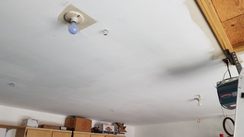 1985 Ford Bronco - A white ceiling with several light fixtures and ceiling hooks is visible. A garage door opener mechanism is mounted to the ceiling on the r…