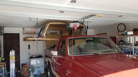 1985 Ford Bronco - A red pickup truck with a removable camper shell is parked in a garage. The camper shell is suspended above the truck bed by straps and woo…