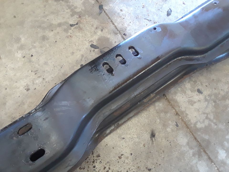 Black metal automotive frame part with cutouts on concrete floor