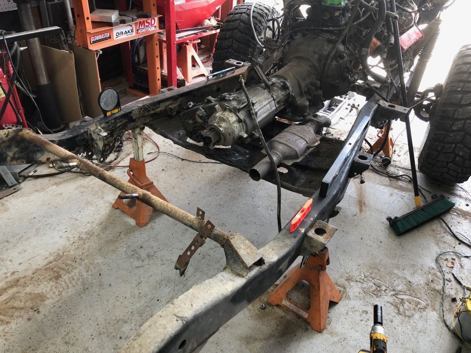 1992 Jeep Wrangler frame on jack stands with transmission and exhaust visible.