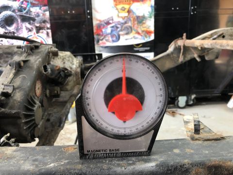 1992 Jeep Wrangler - A protractor with a magnetic base is placed on a rusty metal frame, likely part of a vehicle's chassis. The protractor is positioned to mea…