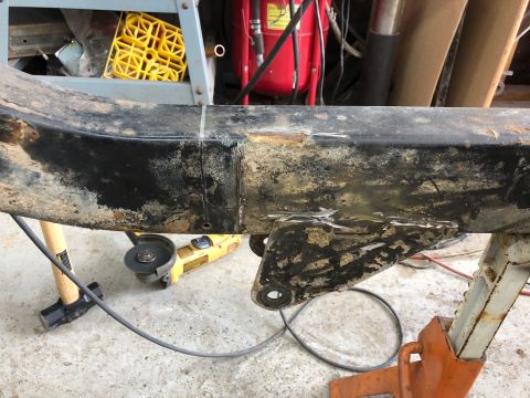 1992 Jeep Wrangler - A rusty, black metal frame section with evidence of recent grinding and repair work. An angle grinder and a sledgehammer are visible on the…