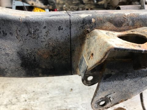 1992 Jeep Wrangler - A close-up view of a heavily rusted and weathered metal frame component, possibly from a vehicle chassis. A vertical black line is drawn on…
