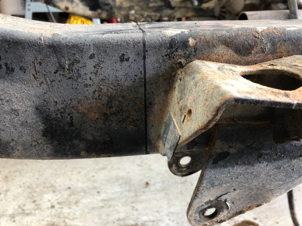 Close-up of a rusty metal frame with a black line drawn on it.