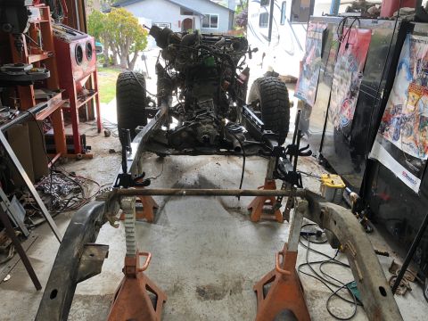 1992 Jeep Wrangler - A Jeep Wrangler frame is elevated on jack stands in a garage, with the engine and transmission assembly partially installed. Various tools…