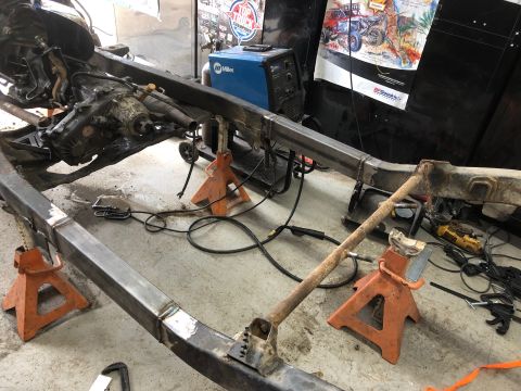 1992 Jeep Wrangler - A Jeep Wrangler frame is shown being worked on in a garage. The frame is supported by orange jack stands and appears to have had modificati…