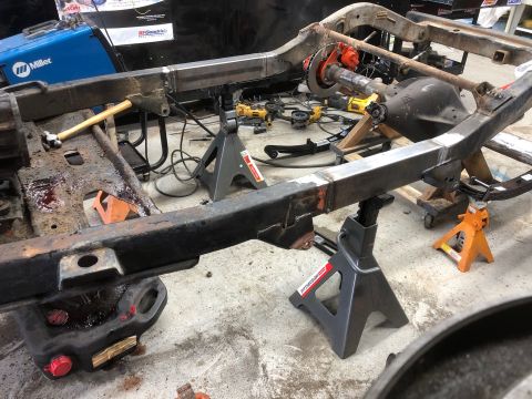 1992 Jeep Wrangler - A Jeep Wrangler frame is supported by jack stands in a garage setting. The frame appears to be undergoing modifications with new metal weld…