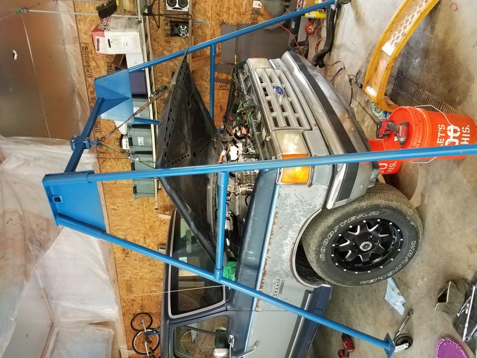 Blue engine hoist over open hood of a pickup truck.