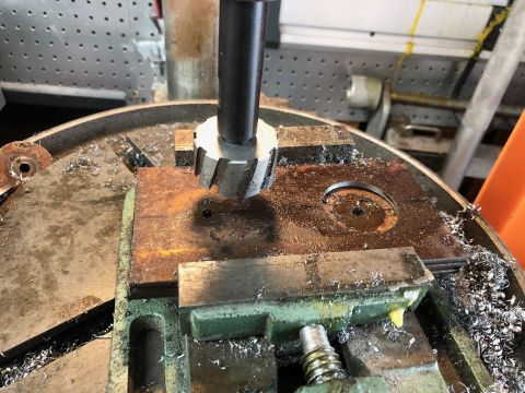 1992 Jeep Wrangler - A milling machine is cutting a piece of metal held in a vise. Metal shavings are scattered around the work area.