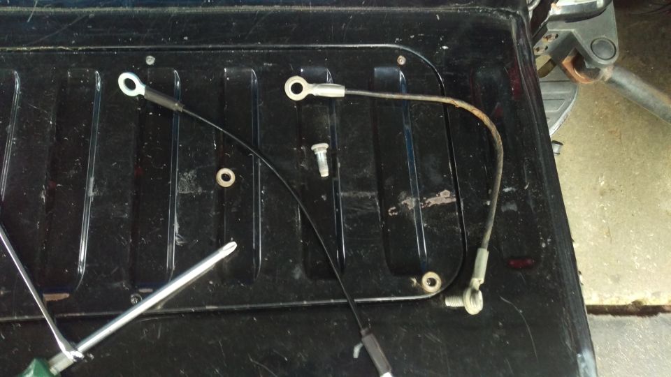 Two cables with eyelet connectors on a black ribbed surface, with a screwdriver and bolt.