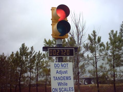 1995 Mazda 626 - A truck is being weighed at a facility with a traffic light and a sign instructing not to adjust tandems.