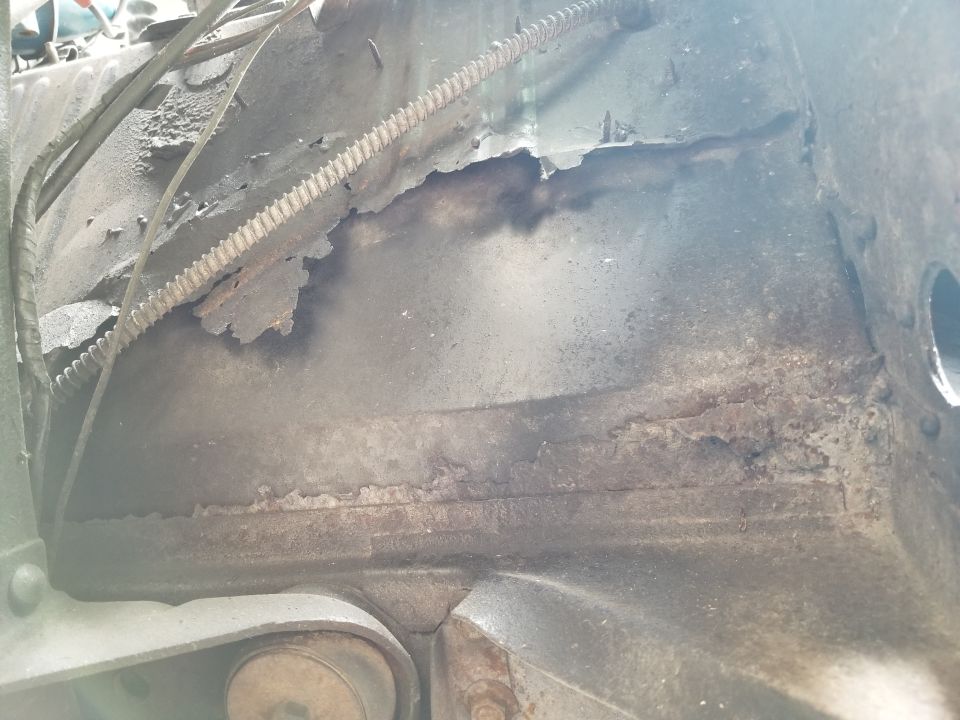 Apparently, many of the holes in the floor were taped before being flooded with Bondo.  Then, more steel was screwed, welded, & seam-sealed on top of the driver's floor (obscuring that body mount bolt).
