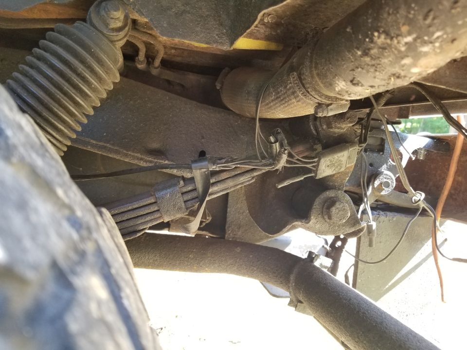 Undercarriage view showing leaf springs, shock absorber, and exhaust pipe