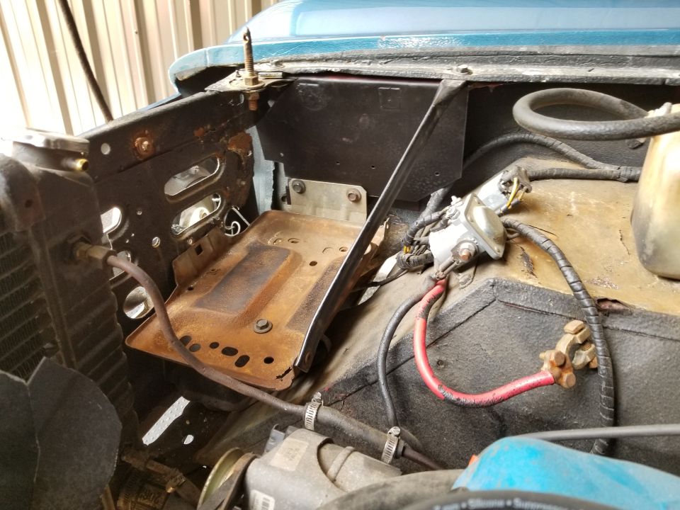 With the custom mounting plate between the fender & inner fender, this '87-96 F-series/Bronco battery tray fits surprisingly well.  And most of the battery's weight will be borne by the top of the inner fender, where it's strongest.  I didn't have to drill any new holes in the original metal, and nothing is welded.

I rearranged the battery cables to fit better, and also cleaned the starter relay terminals. Later, I might replace the battery cable terminals.