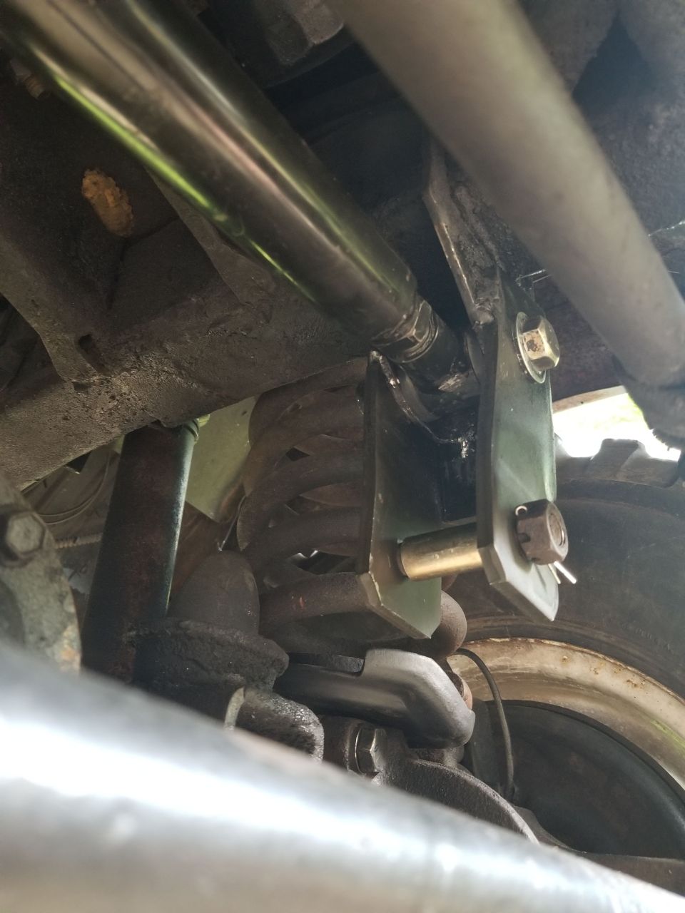 I turned out that this aftermarket adjustable track bar is too long to work in the lower position.  So for now, it's still in the original frame hole, but it's aligned so the steering wheel is straight.
