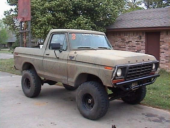 Tan lifted Ford F-series pickup with FORD grille and oversized tires on a driveway