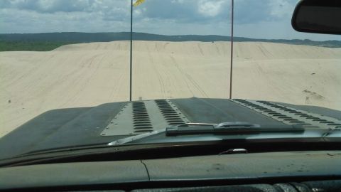 1978 Ford Bronco - View from inside a vehicle looking over the hood at sand dunes. The vehicle appears to be an off-road vehicle with a modified hood featurin…