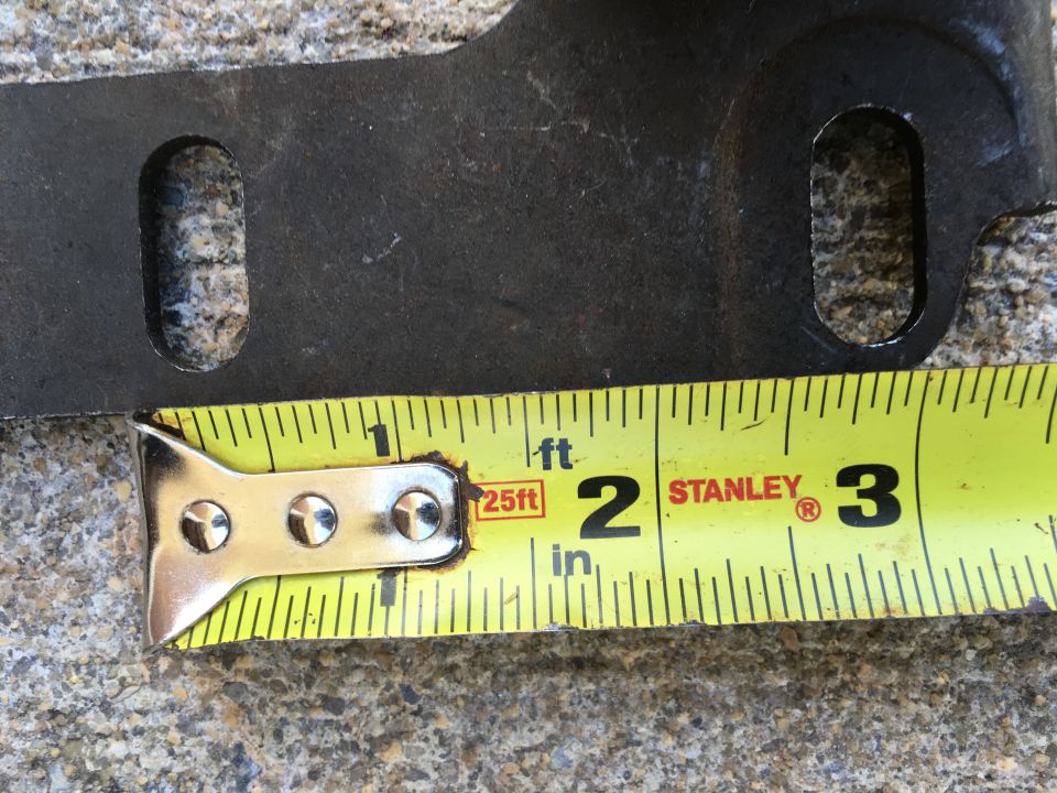 Metal bracket with cutout measured against a Stanley tape measure.