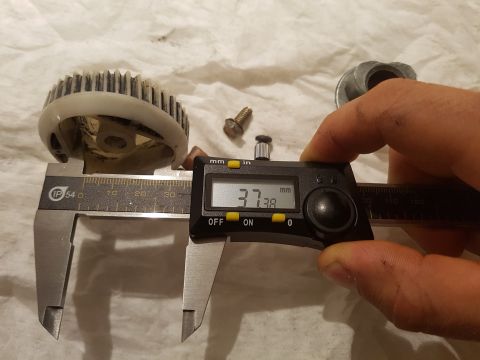 1978 Ford Bronco - A digital caliper measures a gear-like part with teeth, showing a reading of 37.38 mm. The caliper is held by a hand with visible dirt, and…