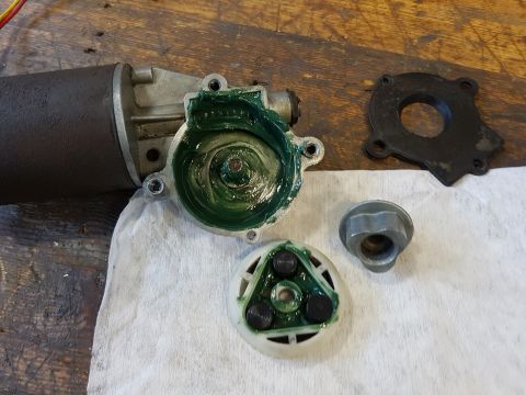 1978 Ford Bronco - A disassembled motor with green grease applied to internal components sits on a white cloth next to a black gasket and a metal nut. The mot…