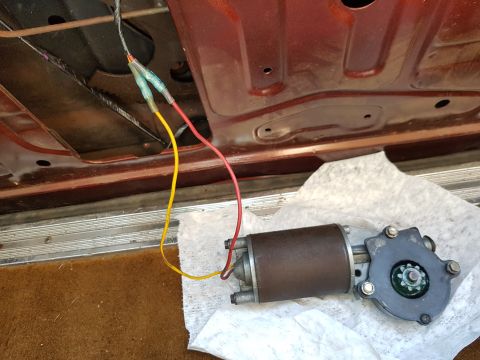 1978 Ford Bronco - Close-up of a car's interior door panel showing a window motor and exposed wiring.