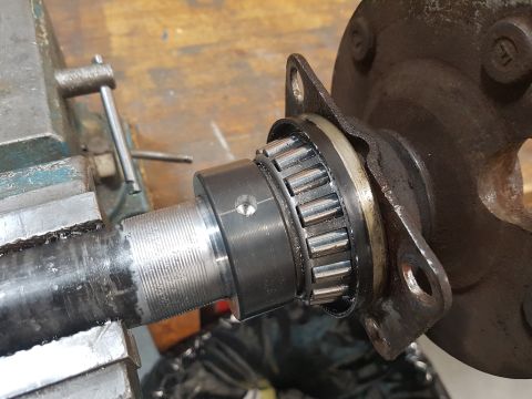 1978 Ford Bronco - Close-up of a vehicle's axle and bearing assembly being worked on in a shop environment with a vise.