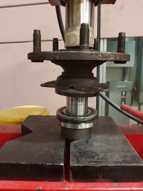 1978 Ford Bronco - A wheel hub and bearing assembly is being serviced on a hydraulic press.