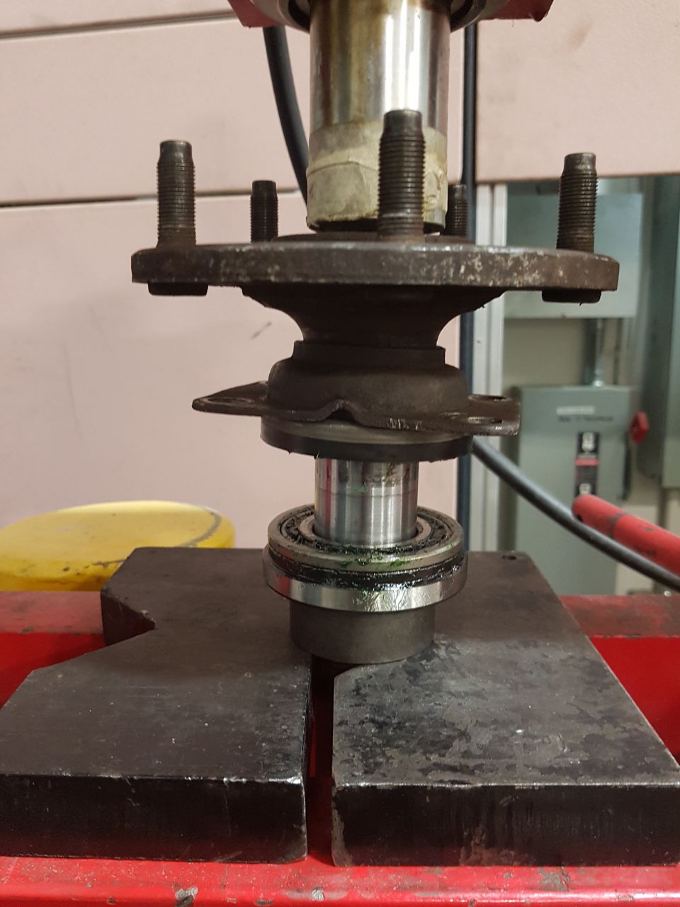 Wheel hub and bearing assembly being pressed on a red hydraulic press