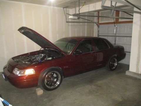 2004 Ford Crown Victoria - A maroon 2004 Ford Crown Victoria is parked in a garage with its hood open, revealing the engine compartment.