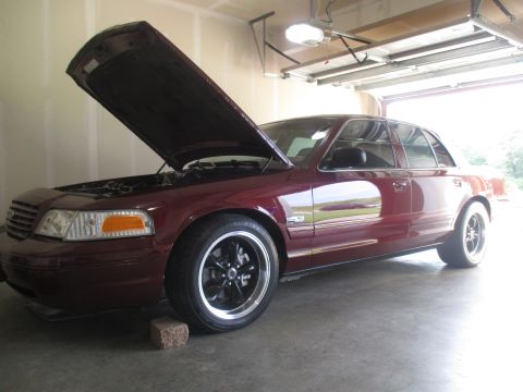 2004 Ford Crown Victoria - A maroon sedan sits in a garage with its hood open, showing off its aftermarket wheels.