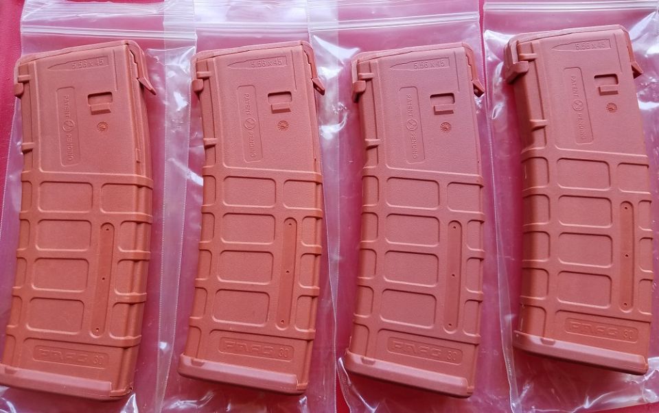 Four tan rifle magazines in plastic packaging, with text 'PMAG 30' visible